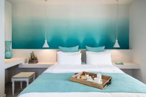 a bedroom with a bed with a tray with two dolls on it at Poseidon of Paros Hotel & Spa in Chrissi Akti