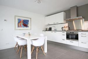 a white kitchen with a white table and chairs at Salt Life Beachhouse in Noordwijk aan Zee