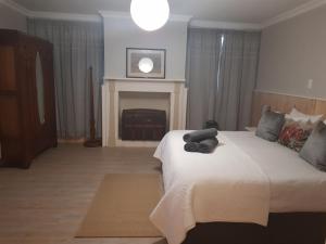 Settler Cottage Apartment في غراهامستاون: غرفة نوم بسرير كبير ومدفأة