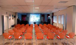 a conference room with orange chairs and a screen at Grunau Hotel in Bayreuth