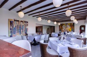 a restaurant with white tables and chairs and lights at No.5 Boutique Hotel in Entebbe
