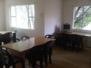 una sala da pranzo con tavoli e sedie e due finestre di Sleek Hostel a Johannesburg