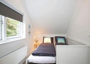 a small bedroom with a bed and a window at Salt Life Beachhouse in Noordwijk aan Zee
