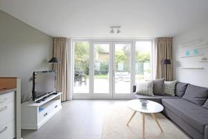 a living room with a couch and a tv at Salt Life Beachhouse in Noordwijk aan Zee
