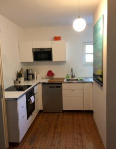 a small kitchen with white cabinets and a wooden floor at Ferienimspessart EG in Bad Soden-Salmünster