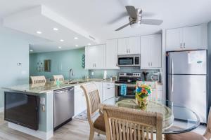 a kitchen with white cabinets and a glass table with chairs at Riverside Club in Marco Island