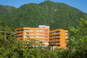 an orange apartment building in front of a mountain at Kurobe UnazukiOnsen Togen in Kurobe