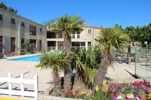 a courtyard with palm trees and flowers next to a building at Domaine Plein Sud in Bruzac