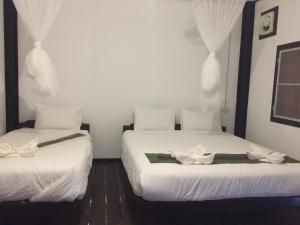 two beds in a room with white sheets at Thongdam Guesthouse in Ban O