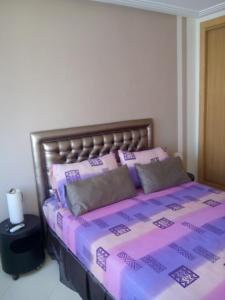 a bed with pink and purple sheets and pillows at location de vacance assilah marina golf in Asilah