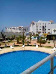 a large swimming pool in a resort with buildings in the background at location de vacance assilah marina golf in Asilah
