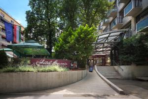una pasarela que conduce a un edificio con una sombrilla verde en Benczur Hotel, en Budapest 37 fotos más