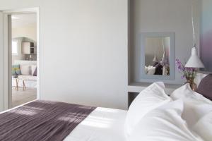 a bedroom with a white bed and a mirror at Poseidon of Paros Hotel & Spa in Chrissi Akti
