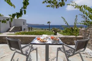 a table with food and drinks on a patio with the ocean at Poseidon of Paros Hotel & Spa in Chrissi Akti