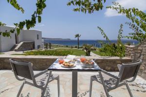 a table with food and drinks on a patio with the ocean at Poseidon of Paros Hotel & Spa in Chrissi Akti