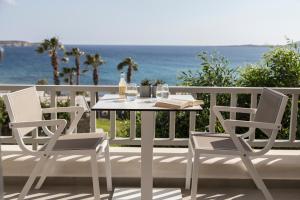 a white table and chairs on a balcony with the ocean at Poseidon of Paros Hotel & Spa in Chrissi Akti