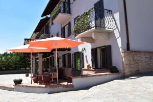 an outdoor patio with tables and umbrellas in front of a building at B&B La Dolce Vita in Priocca