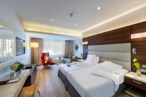 a hotel room with two beds and a woman sitting in a chair at Amathus Beach Hotel Limassol in Limassol