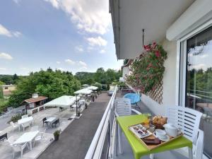 d'un balcon avec une table verte, des chaises et des tables. dans l'établissement Logis Hotel Maison Carrée Restaurant O Carré dArt, à Méréville