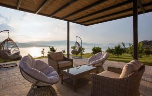 a patio with chairs and tables and a view of the water at Villa Soumela in Nikiana