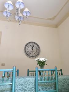 un reloj en la pared sobre una mesa con sillas en Casa Jolanda B&B en Palermo