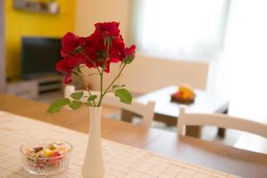 a white vase with red flowers on a table at Stay In Touch in Gospić