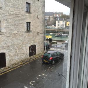 un'auto parcheggiata in una strada sotto la pioggia da una finestra di Sailors Return Weymouth a Weymouth