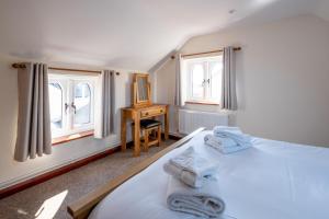 1 dormitorio con 1 cama, escritorio y 2 ventanas en 3 Beach Cottages - Aldeburgh Coastal Cottages, en Thorpeness