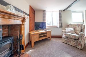 a living room with a fireplace and a chair and a desk at 3 Beach Cottages - Aldeburgh Coastal Cottages in Thorpeness