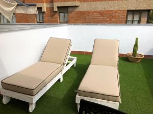 two chairs on a patio with green grass at SevillaHome - Marqu&eacute;s de Paradas in Seville