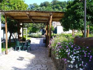 een houten pergola met een tafel, stoelen en bloemen bij Hotel La Marticana in Ischia