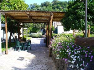 a wooden pergola with a table and chairs and flowers at Hotel Villa La Marticana in Ischia