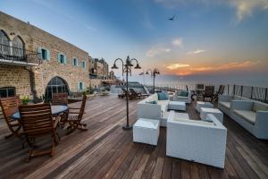 a deck with couches and tables and chairs and the ocean at Casa Nova - Luxury Suites & Boutique Apart-Hotel in Tel Aviv