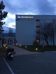a person sitting on a motorcycle in front of a building at Best Western Alexander Park Chambéry in Chambéry