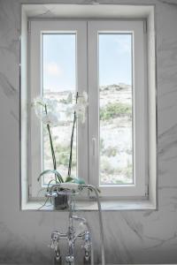 a bathroom with a window and a sink with a flower at Cesca's Boutique Hotel in Xlendi