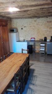 ArchignacにあるAu Tilleulの大きな木製テーブルとキッチンが備わる客室です。