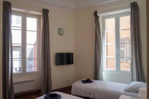 a bedroom with two beds and a tv on the wall at Magnifiques Appartements au coeur du Vieux Nice in Nice