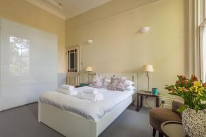 um quarto com uma cama com lençóis brancos e almofadas em Lovely Chelsea Home near The Thames by UndertheDoormat em Londres