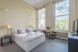 - une chambre avec un lit blanc et 2 fenêtres dans l'établissement Lovely Chelsea Home near The Thames by UndertheDoormat, à Londres
