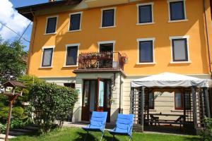 a group of blue chairs in front of a yellow building at Locanda Aurora-garnì in Asiago