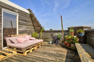 een bank op een houten terras met bloemen en planten bij Rooftop studio near Amsterdam Castle (Muiden) in Muiden