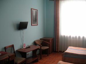 a room with a bed and a desk and a bed and a room at Kargopol Hotel in Kargopol'