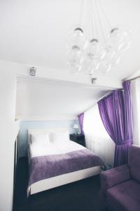 トヴェリにあるApartamenty Family Labのベッドルーム1室(紫色のカーテンとシャンデリア付きのベッド1台付)