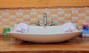 lavabo con bañera blanca con grifo en Lake Mulehe Gorilla Lodge en Kisoro