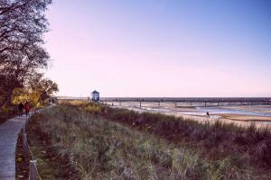 people walking along the beach with a pier in the background at Ferienwohnung Urlaub in Greifswald