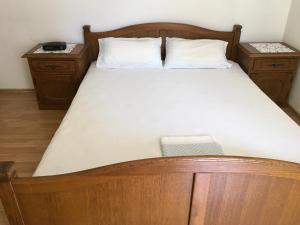 a bed with a wooden frame and two night stands at Apartman Nadia in Karlobag