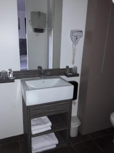 a bathroom with a sink and a mirror and a toilet at Hôtel Le Cosy Blois Villebarou in Blois