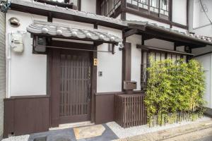 京都市にあるTsurui Goshonishi 鶴居御所西の茶色の扉と茂みのある家