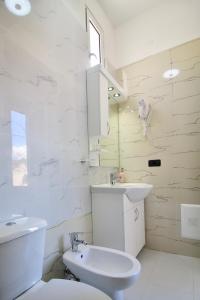 a white bathroom with a toilet and a sink at Hotel Orestiada in Berat
