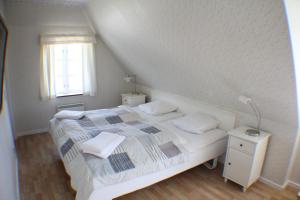 a small bedroom with a white bed with a window at Klitgaarden Henne Strand in Henne Strand